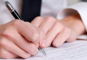 person's hand signing an important document