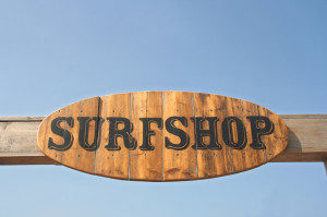 Wooden sign at the beach saying Surfshop