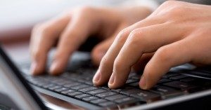 Close-up of male fingers typing a business document on the black laptop